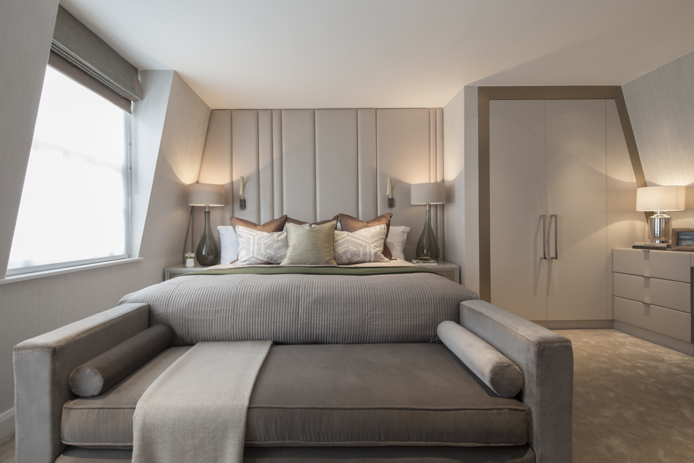 elegant bedroom in cream and champagne with leather headboard and chaise lounge at foot of bed