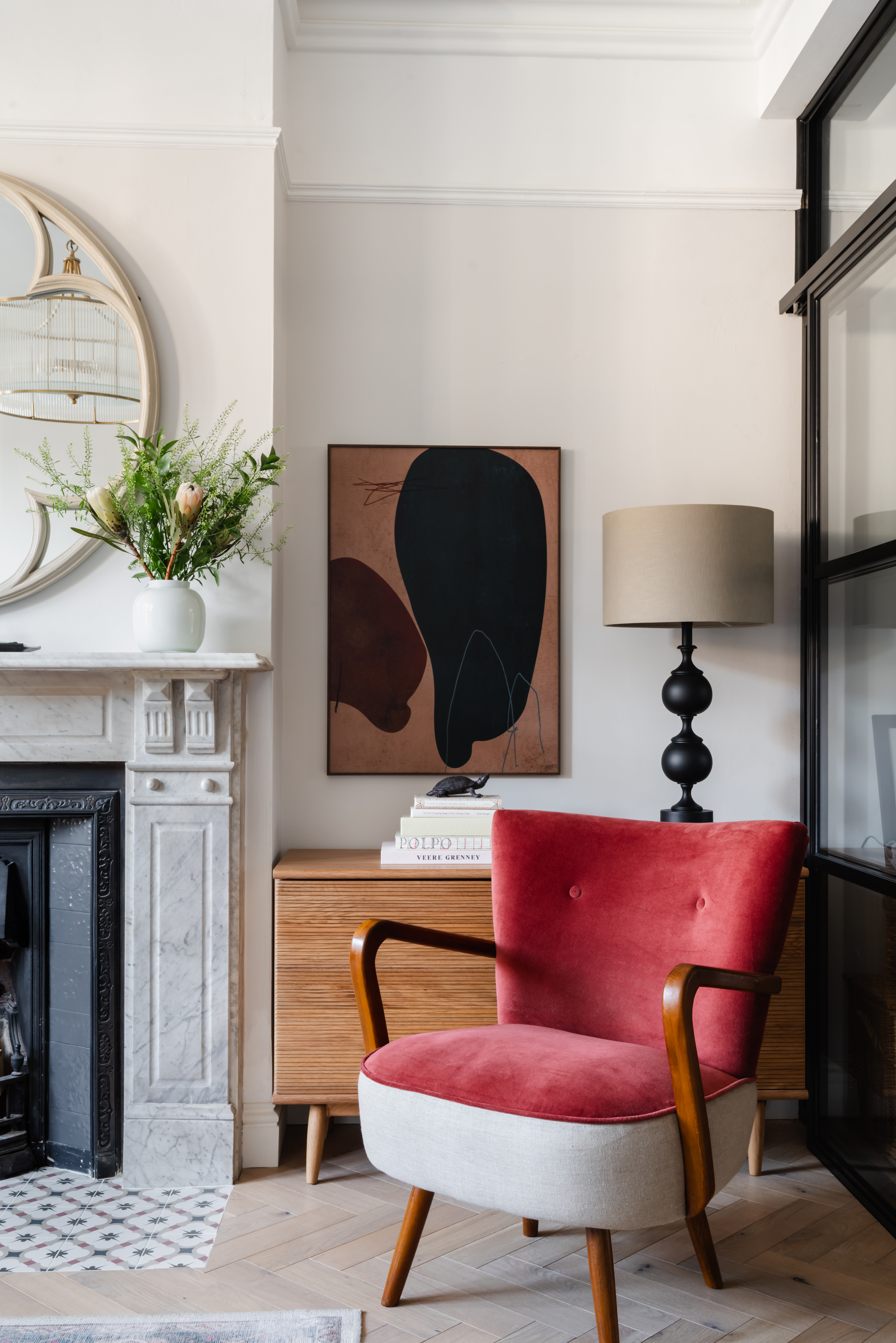 Mid-century modern terracotta velvet armchair (Atkin & Thyme) paired with contemporary abstract artwork, creating a sophisticated reading corner.