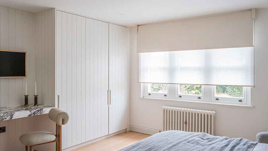 Bedroom with VENESTRE made-to-measure roller blinds in a neutral blackout and sheer fabrics, fitted above classic sash window. The bespoke window treatments enhance privacy and daylight, showcasing VENESTRE’s expertise in luxury window dressing for modern interiors.