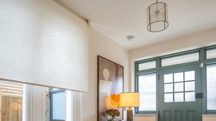 Contemporary entry hall with VENESTRE made-to-measure roller blind in a light-filtering fabric, installed above large window. The bespoke window treatment enhances privacy and daylight, reflecting VENESTRE’s commitment to minimal elegance and premium interior solutions.