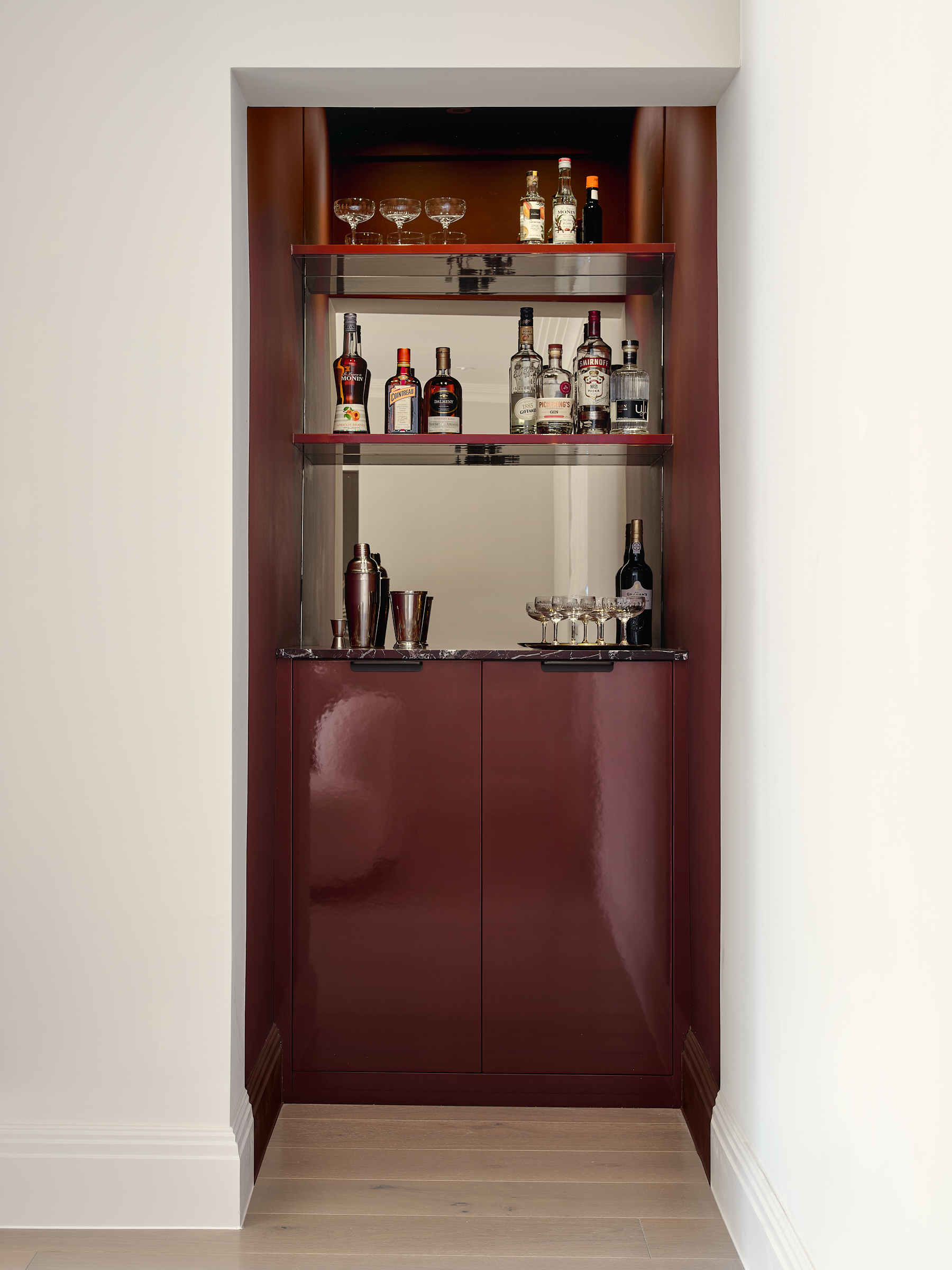 Concealed in the family room we added an oxblood red gloss joinery with mirrored back-panel