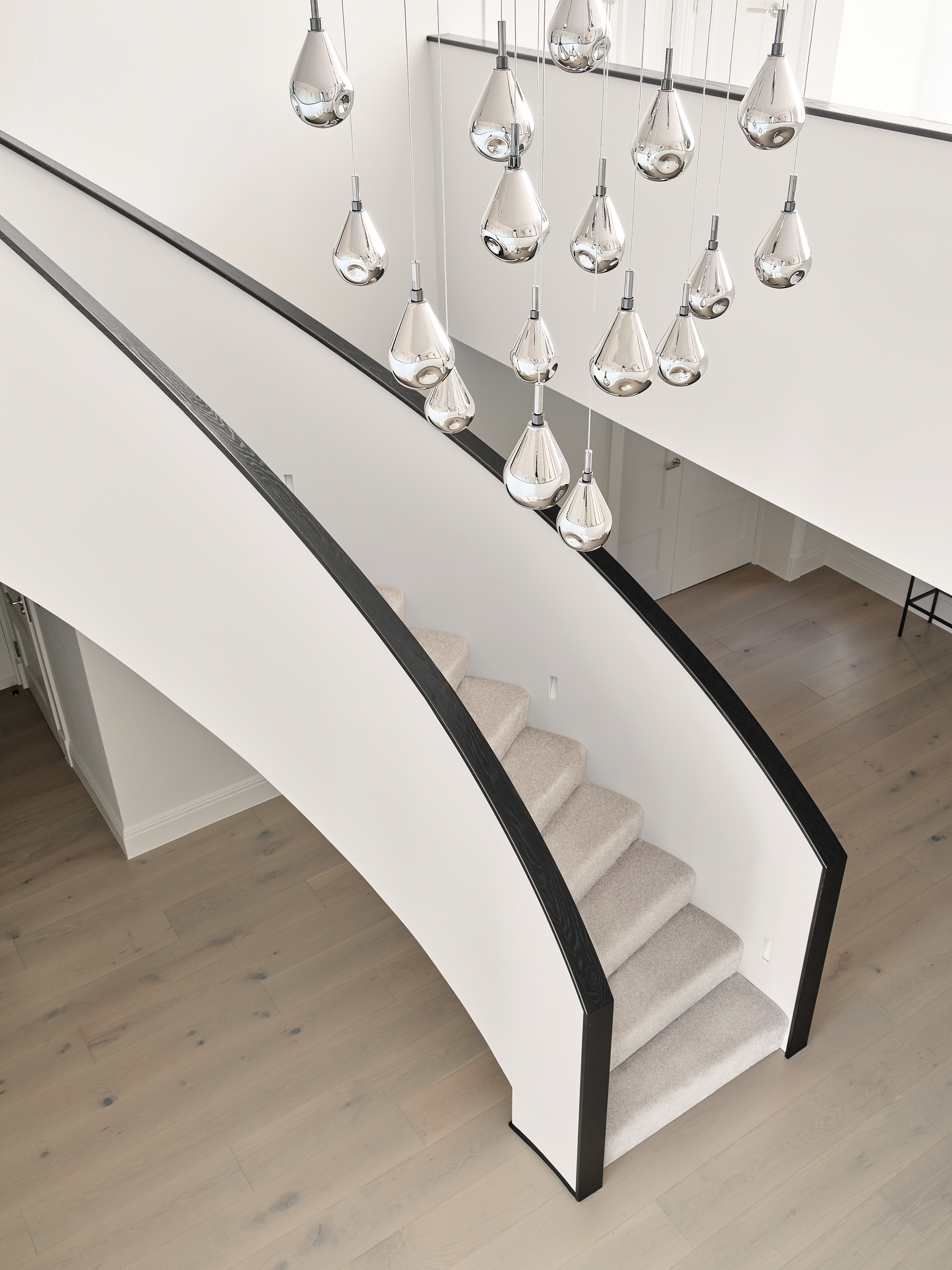 Vaulted hallway with Restoration Hardware pendant light and bespoke curved staircase with dark wood handrail