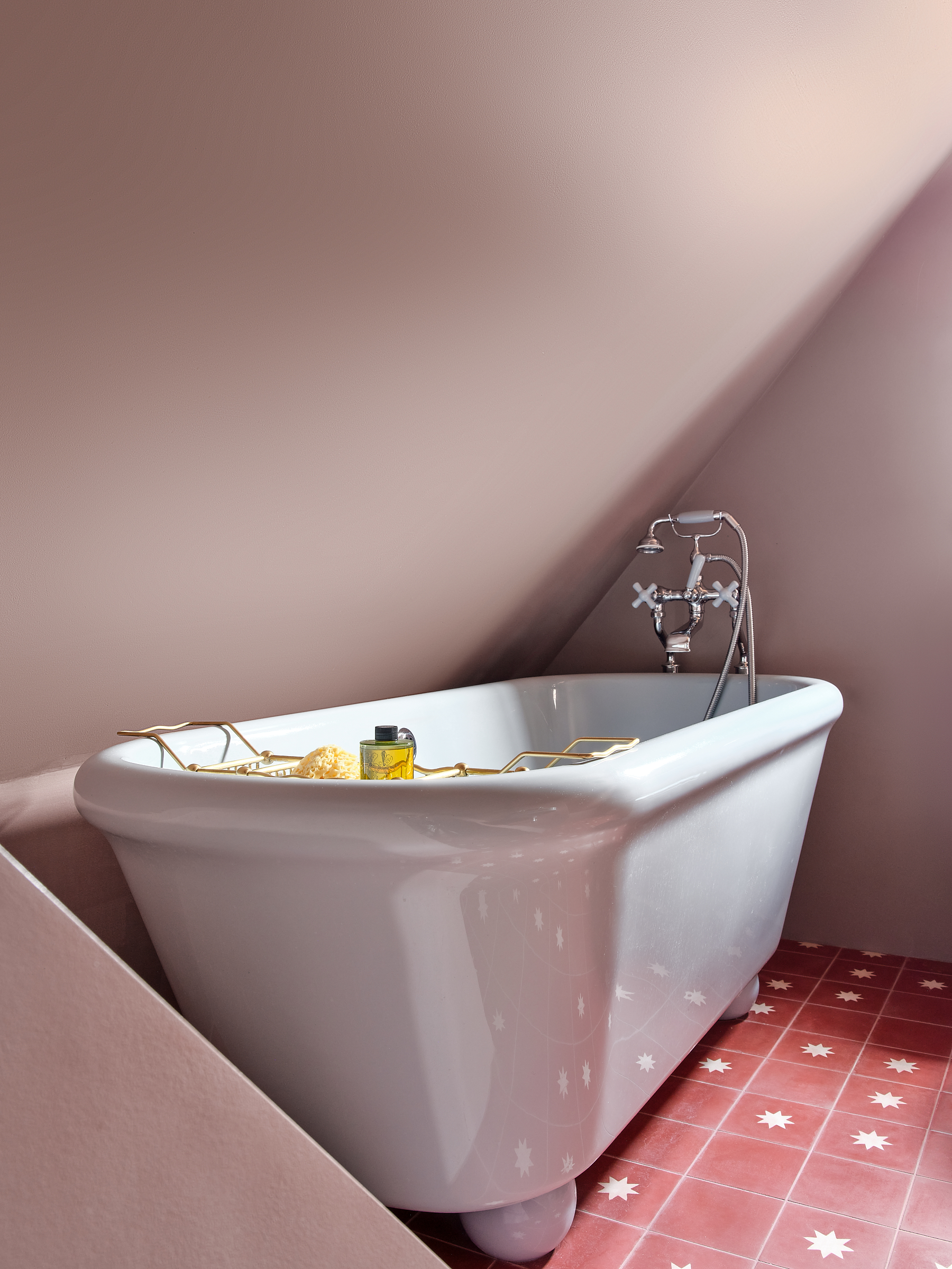 Water Monopoly bath in blue on ball feet in dusky pink bathroom with encaustic floor tiles with stars on pink