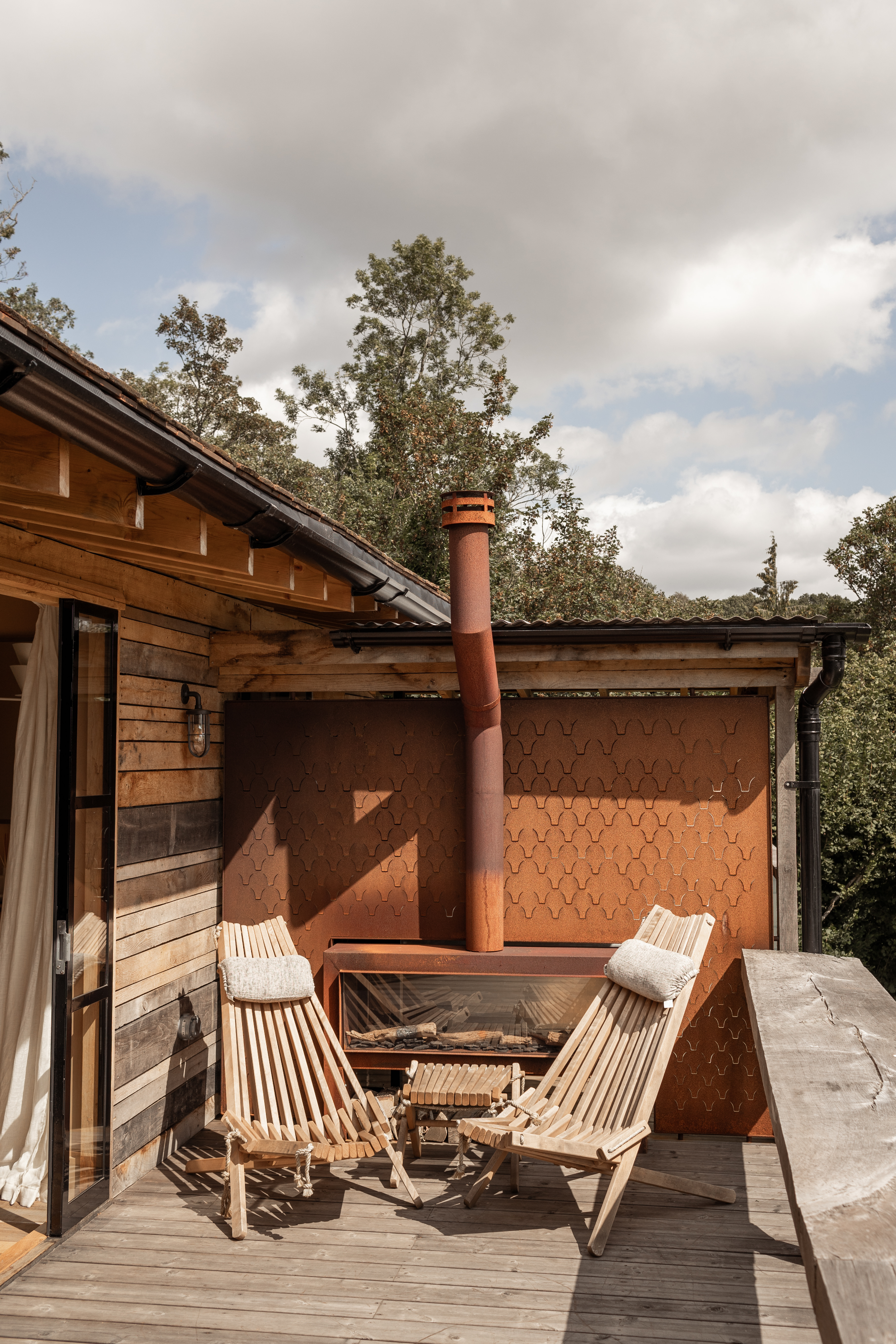 Private decked terrace with outdoor fireplace clad in bespoke corten screen wall