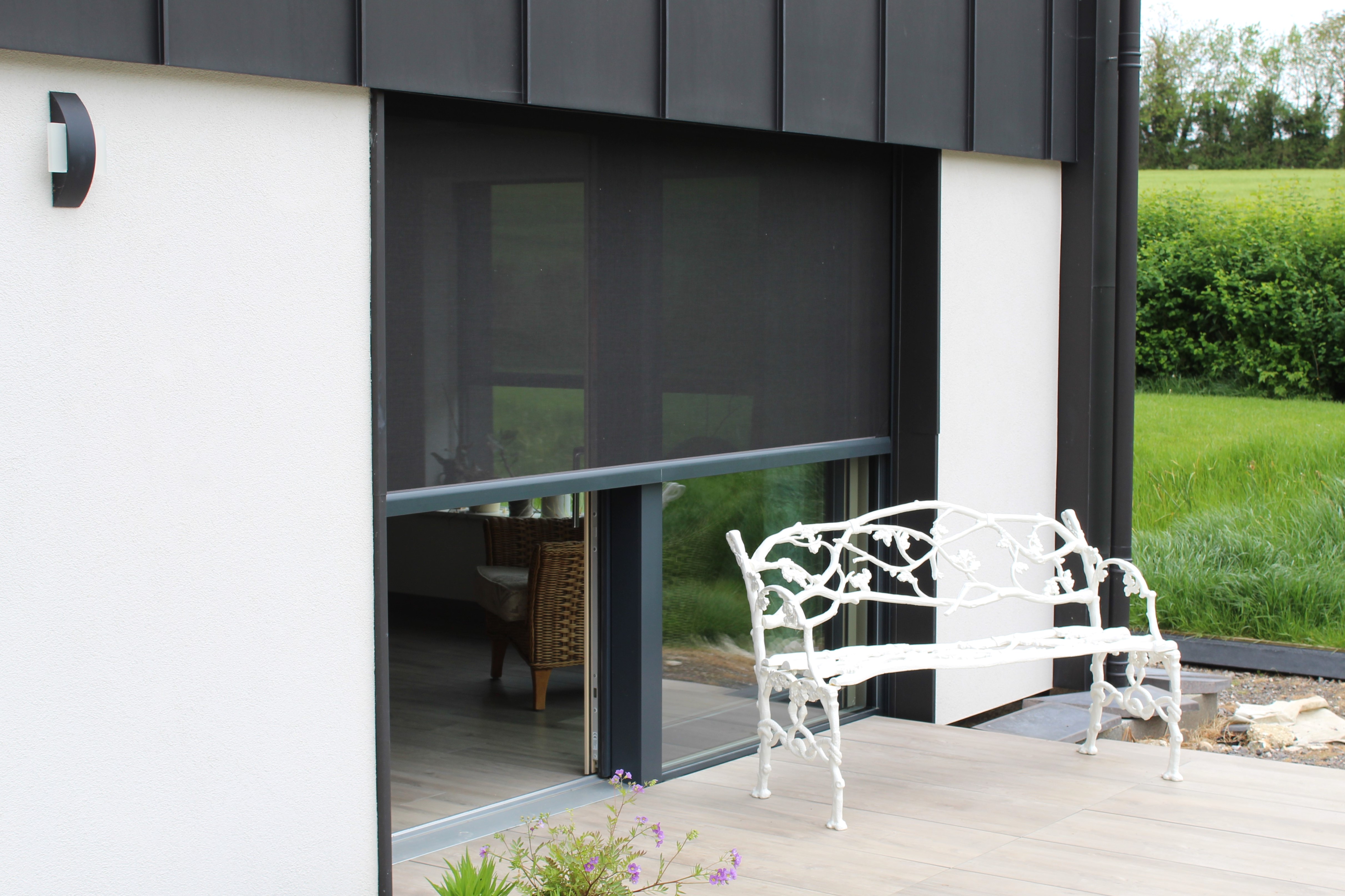 Exterior view of solar screens blending with the modern facade of a Passive House to control solar gain