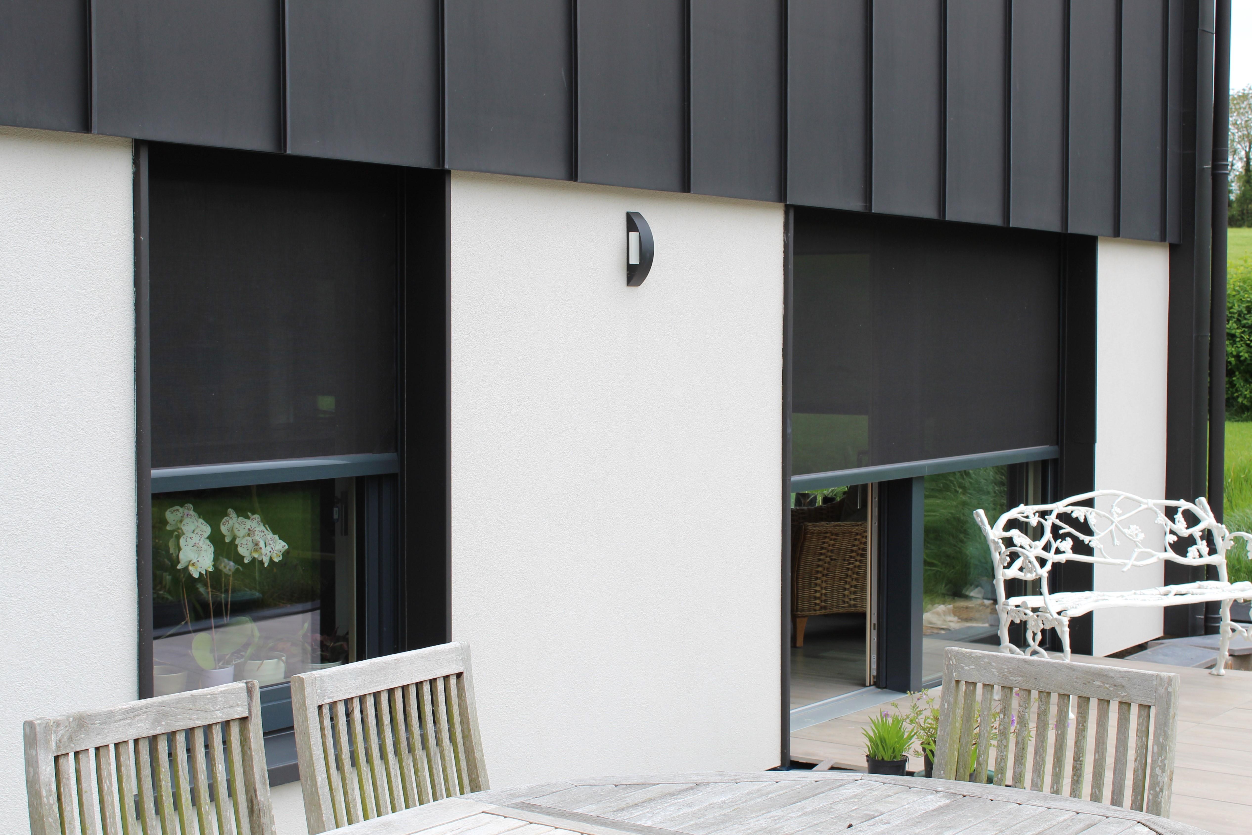 Solar screens deployed to filter sunlight and manage indoor temperature in an energy-efficient home