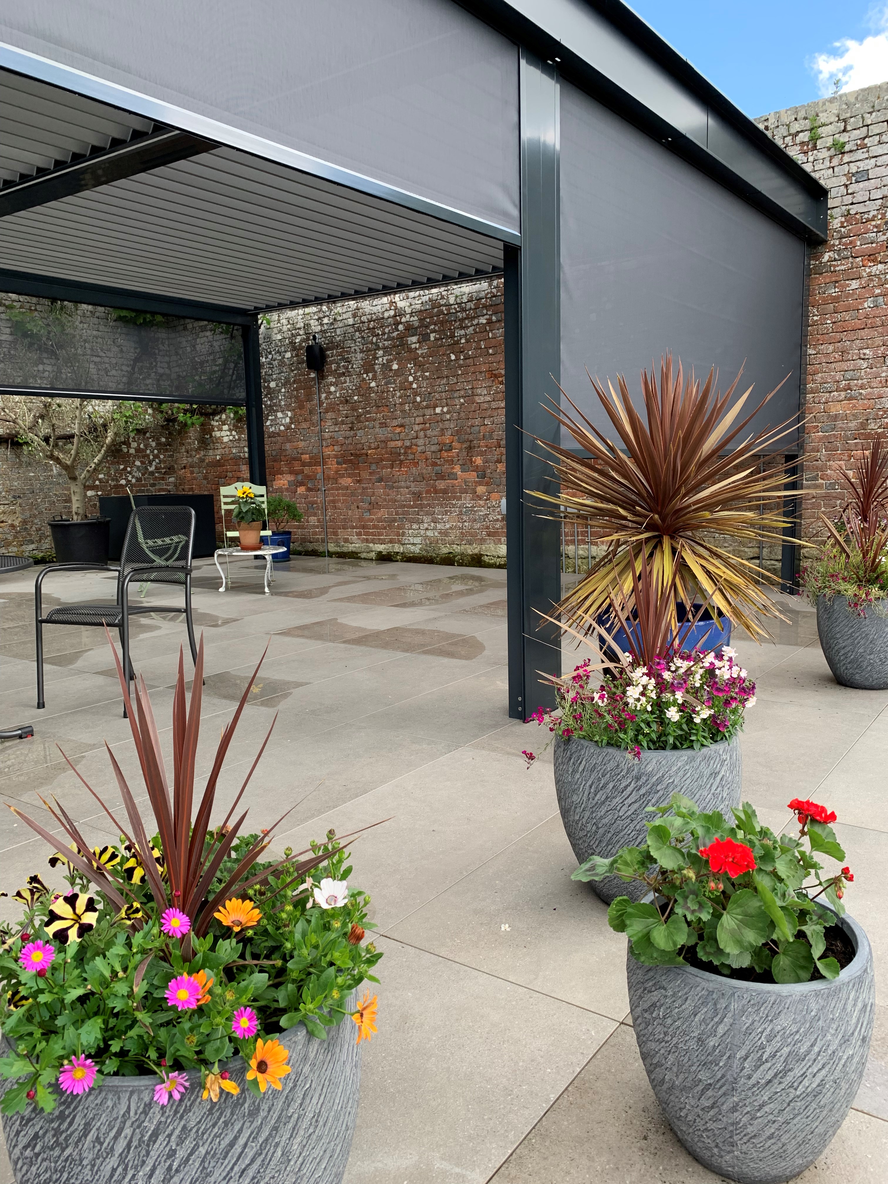 Automated screens extending down in the pergola, providing sun and insect protection