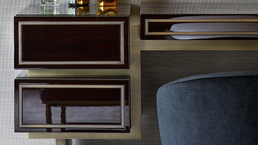 Close-up of luxury dressing table with high-gloss wood finish, gold trim detailing, and integrated drawers paired with a plush velvet chair in a refined interior
