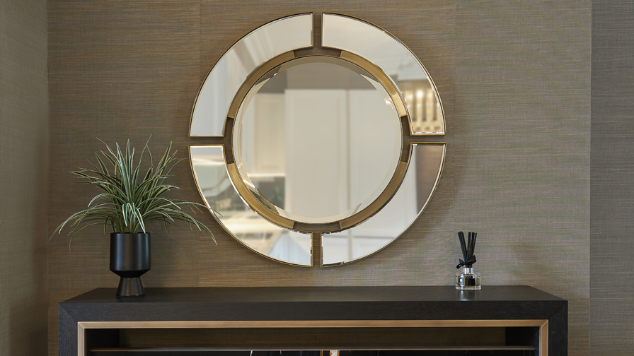 Contemporary luxury console styling with circular segmented gold-framed mirror, dark wood sideboard with brass detailing, and minimalist décor in a refined interior setting