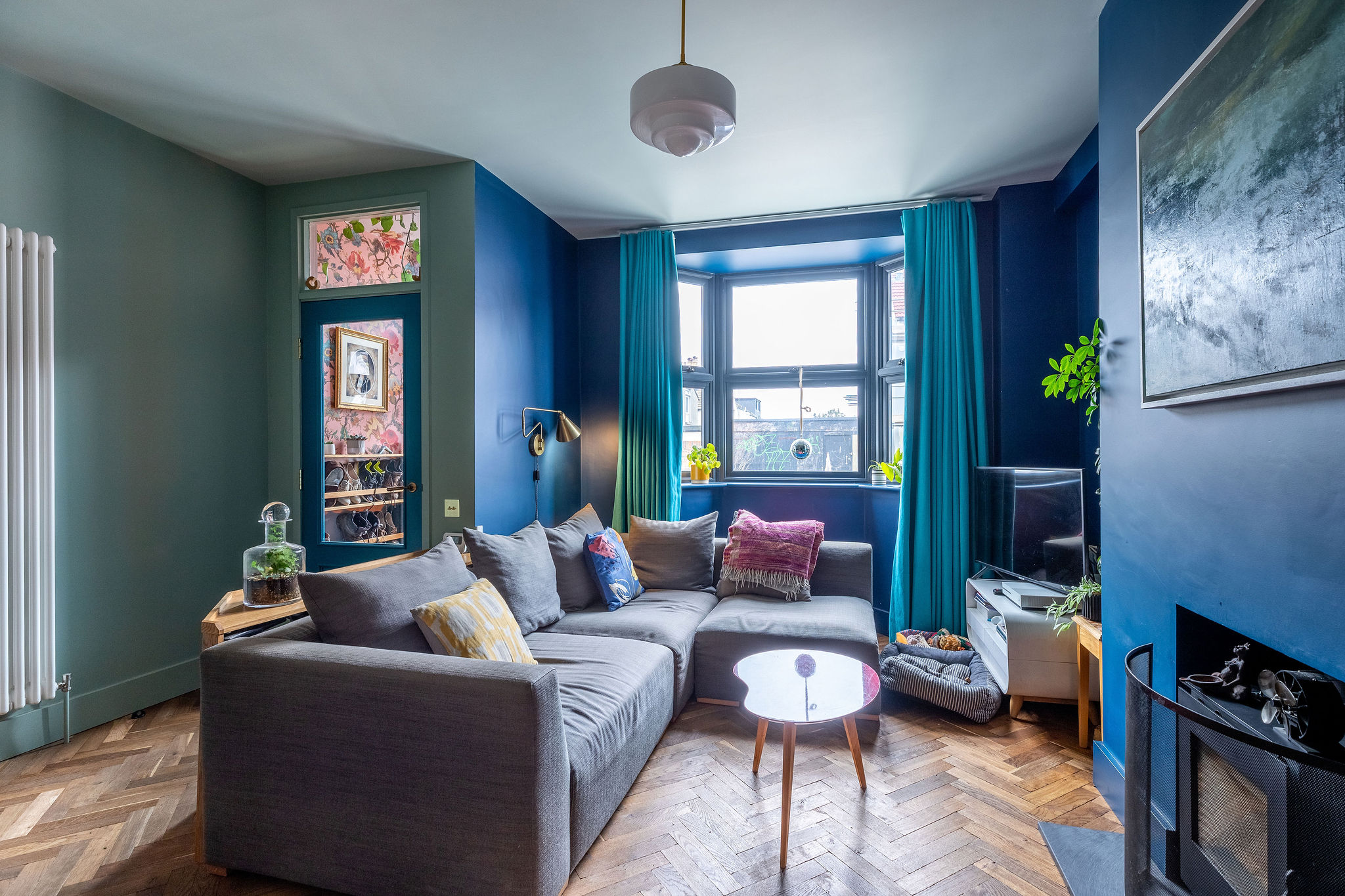 Blue lounge with parquet flooring and wallpapered entrance