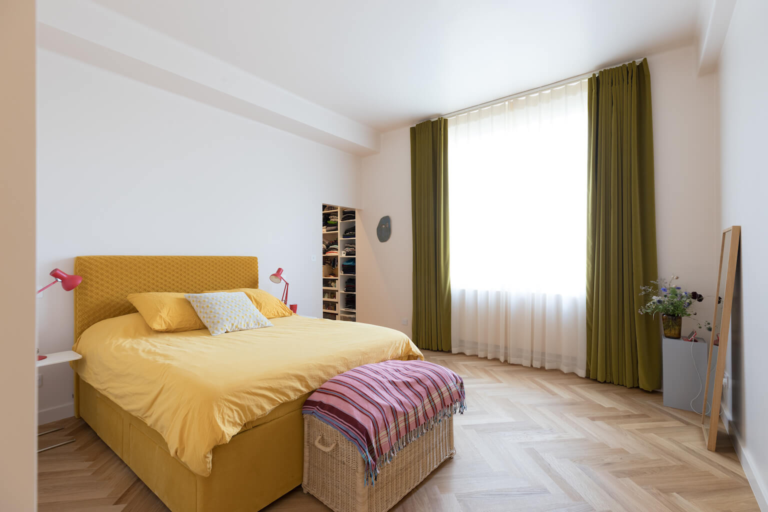 large luxurious bedroom with green curtains, yellow bed and parquet flooring