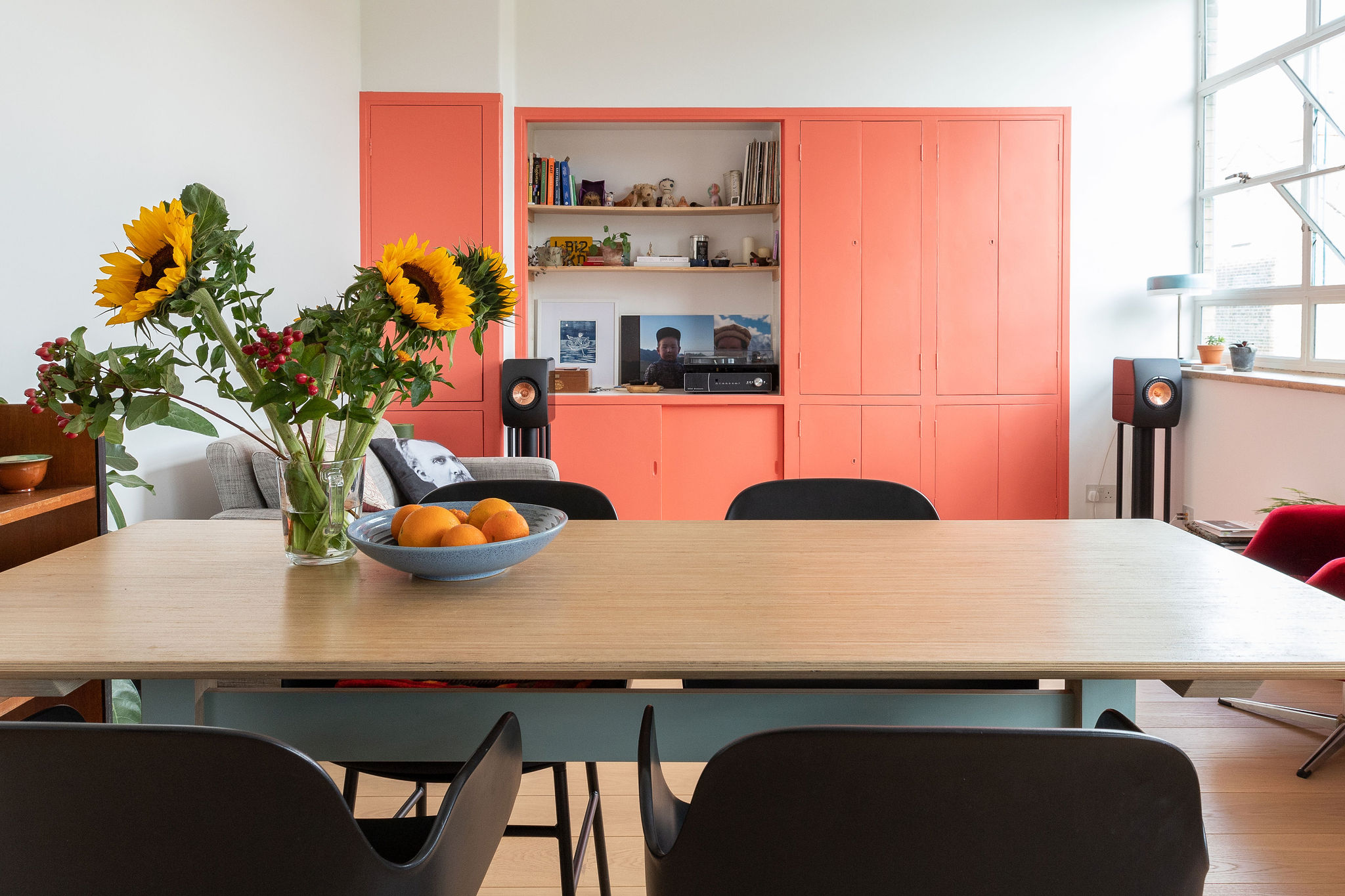 sunflowers on the table in front of coral painted joinery in the dining room/lounge