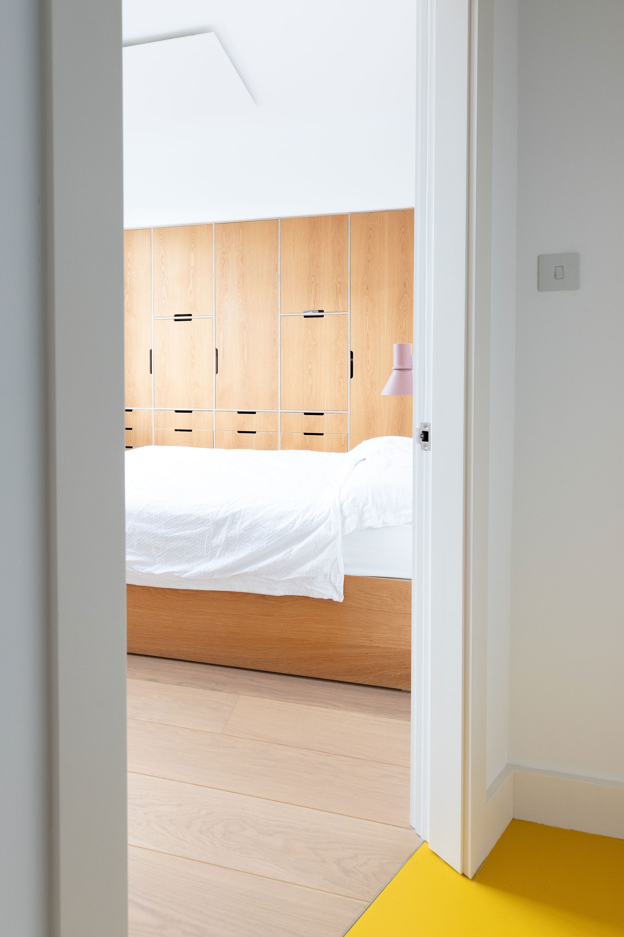looking through the door frame into the bedroom with beautiful joinery and bed