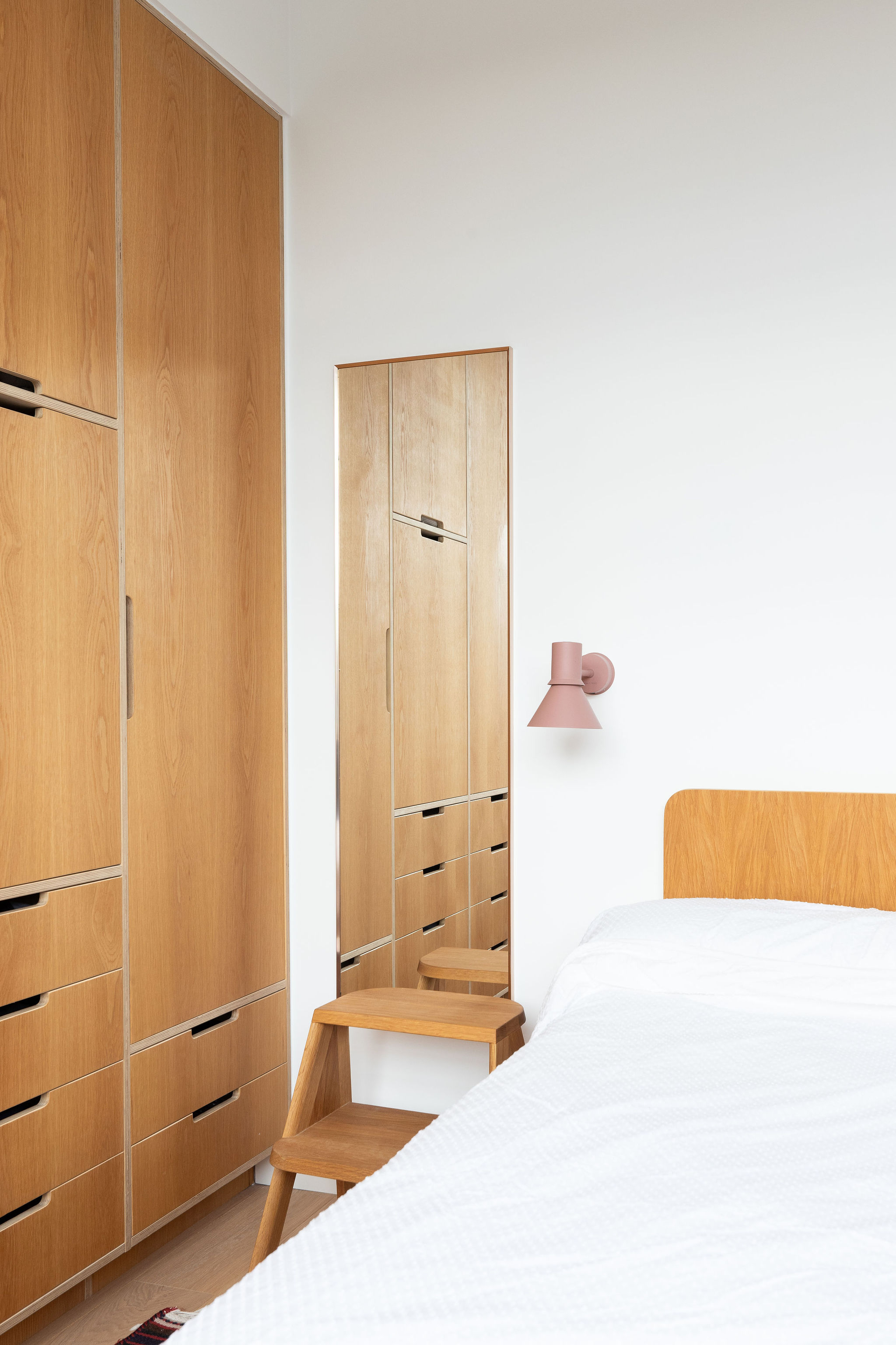 Beautiful matching wooden furniture in the bedroom with white walls and white linens 