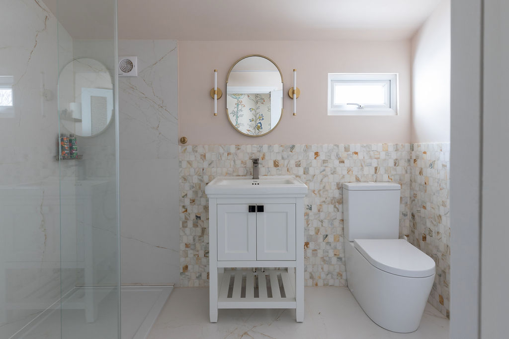 Bathroom decorated with beautiful marble tiles and plastery pink paintwork, combined with new lighting & fittings