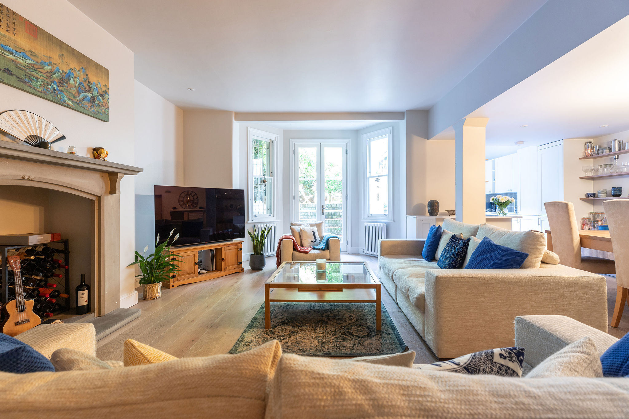 Neutral lounge with wooden floors, large fireplace and two dofas with blue accent cushions 