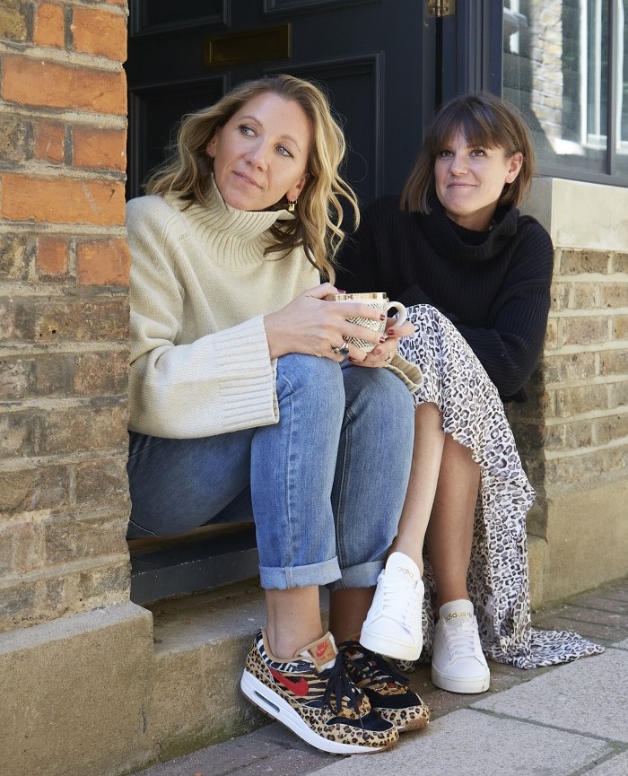 Two women sitting on a front door step.