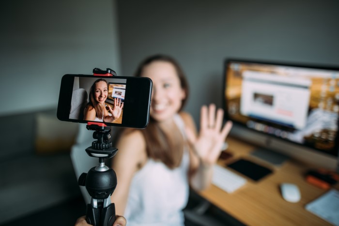 woman at her desk filming herself on her phone