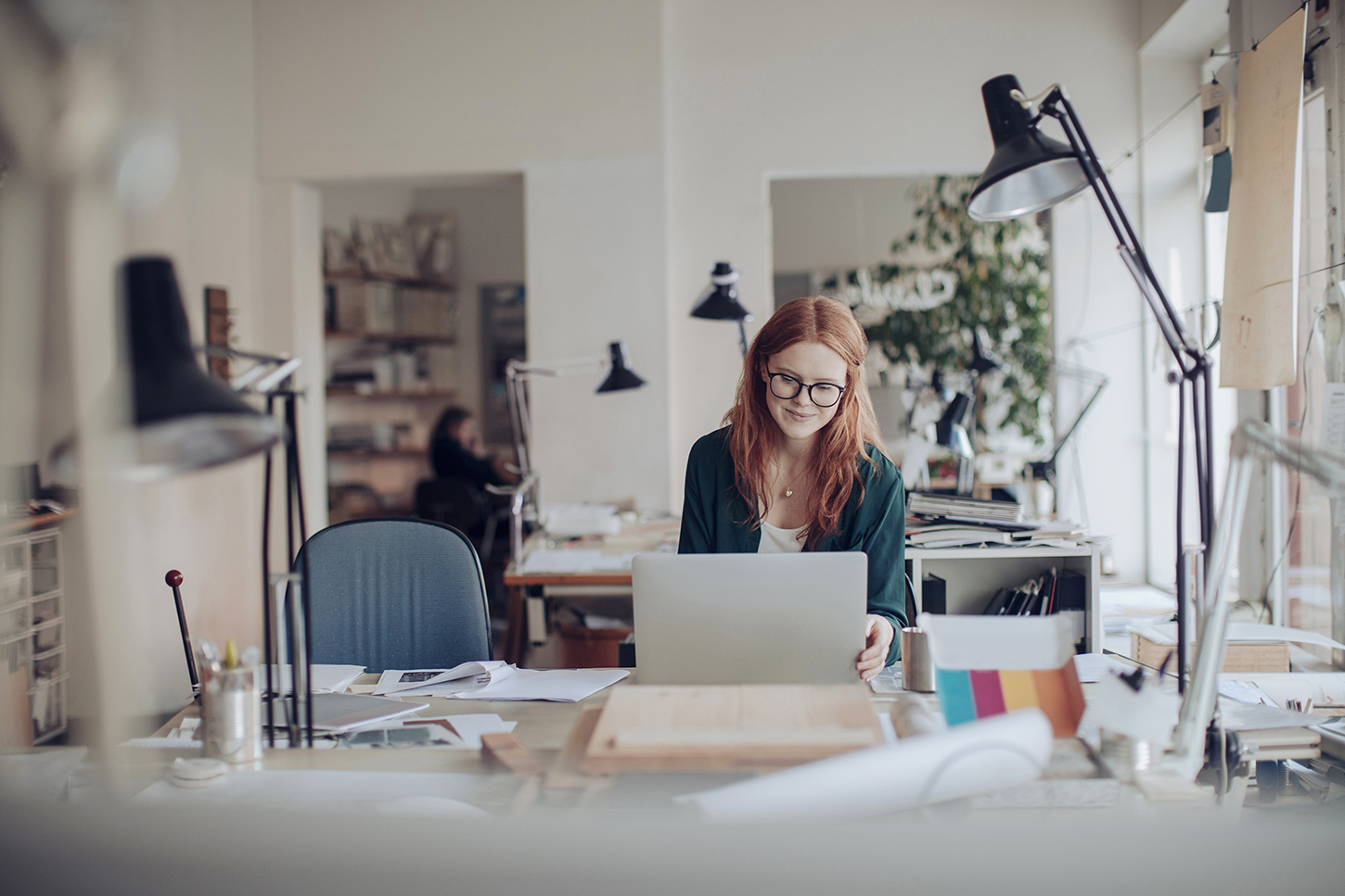 woman behind a desk working at a laptop