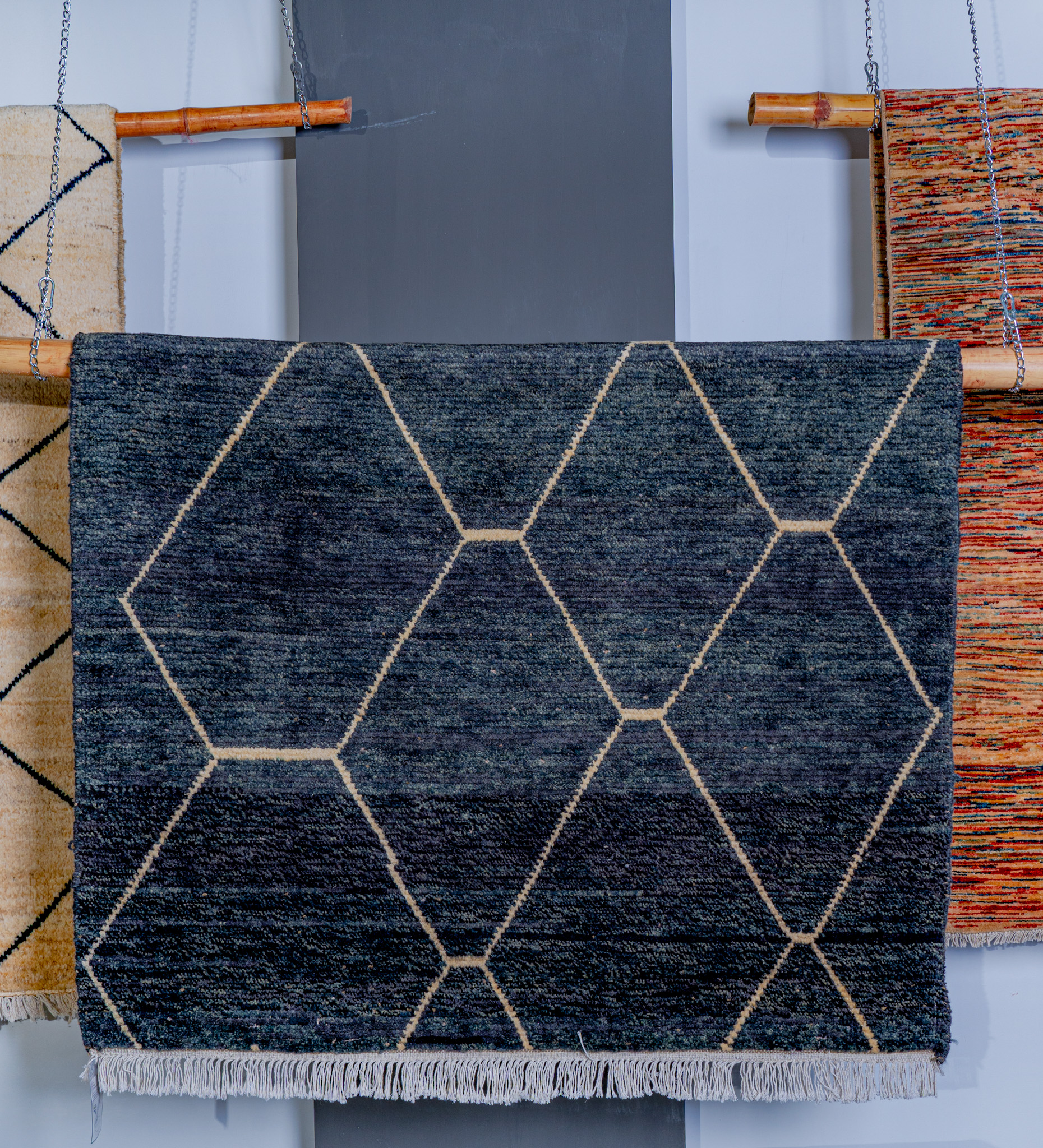 hand-knotted, plush, Moroccan-style rug in a deep charcoal-blue, featuring a clean, geometric diamond-lattice pattern in a cream line, hung for display.