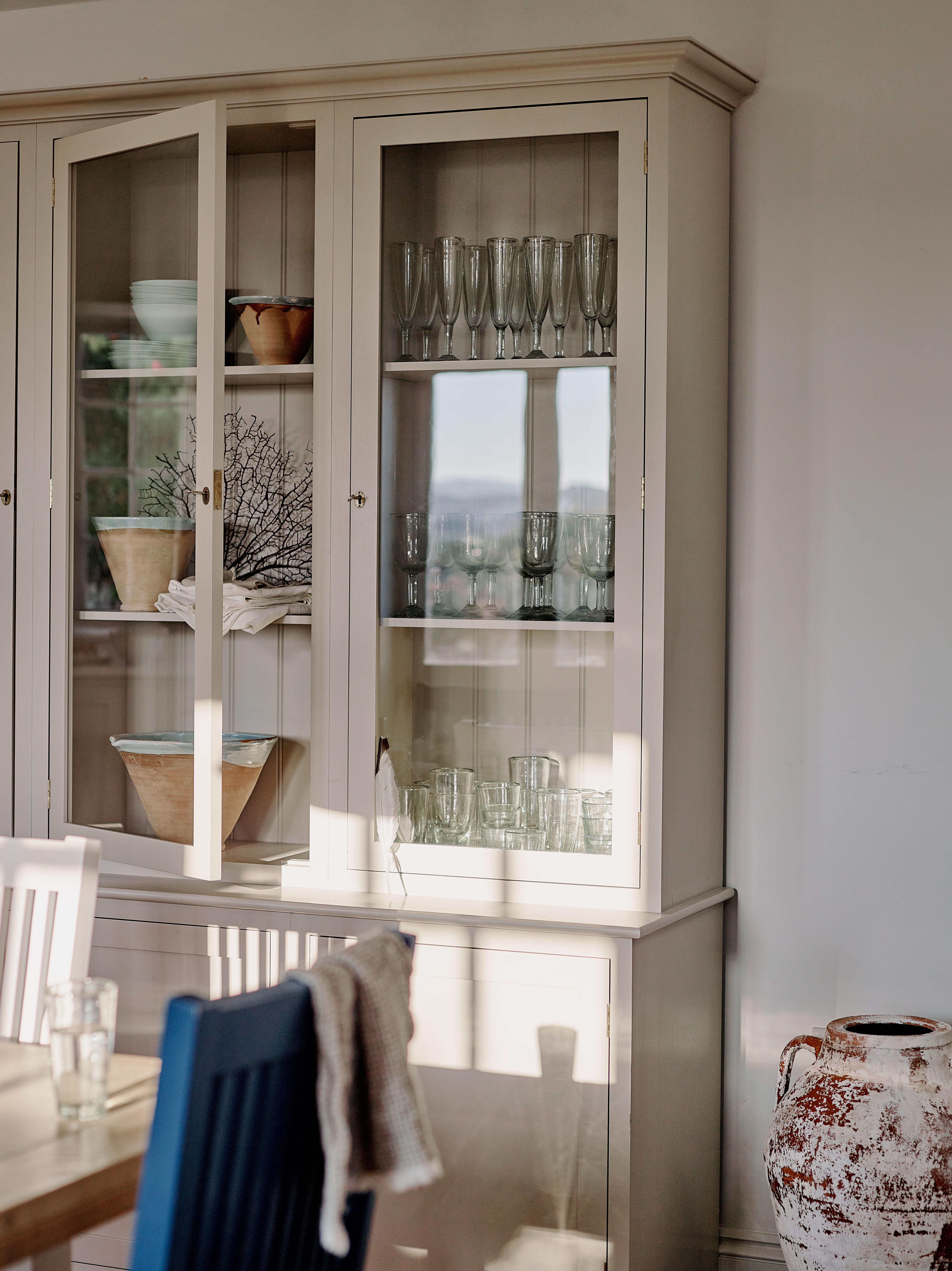 Dining area storage in a restored West Cornwall cottage, with glazed cabinetry and carefully chosen tableware, part of a full interior architecture and furnishing project.