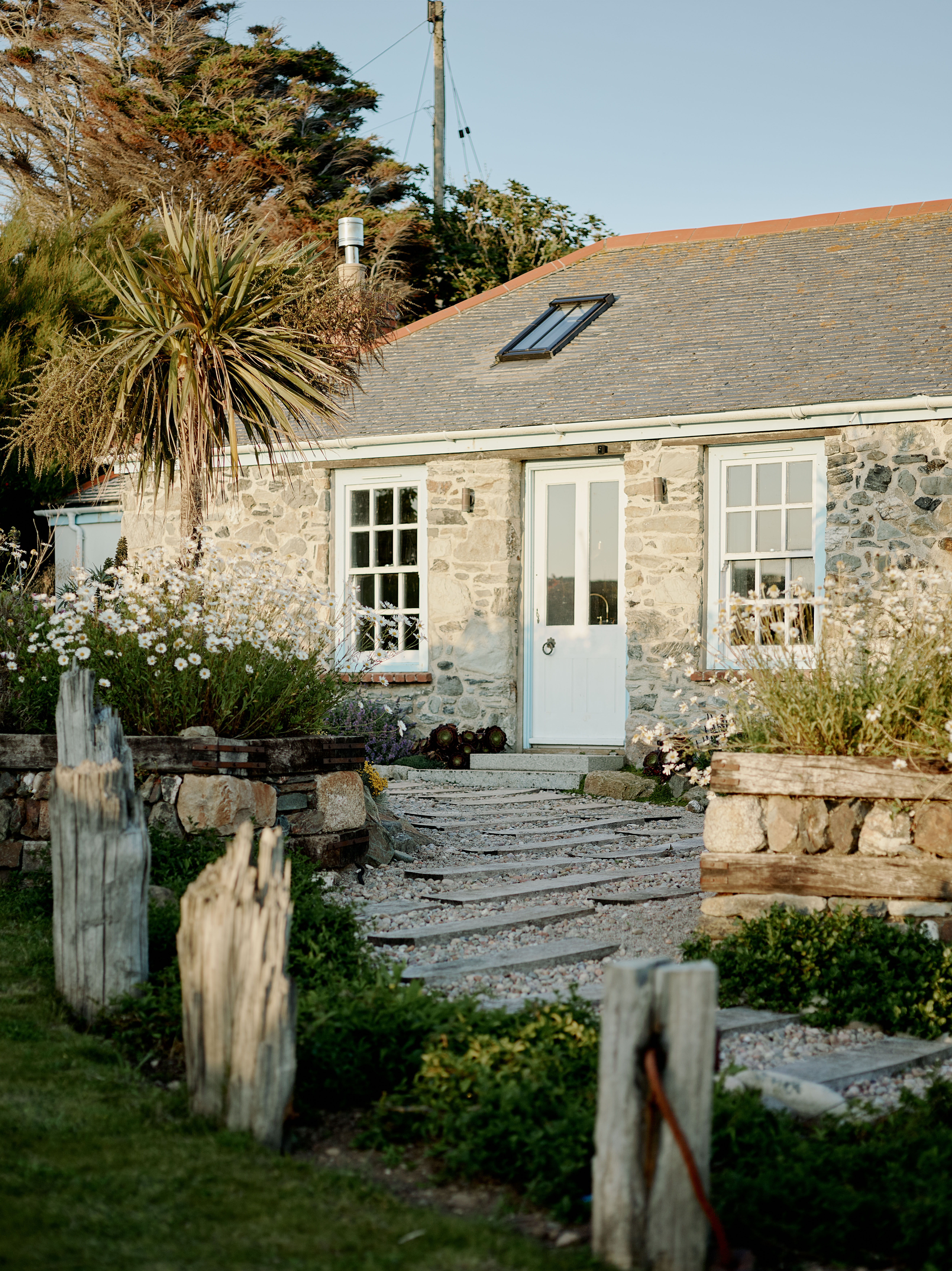 Exterior of a remote West Cornwall stone cottage following a full renovation and interior architecture project, set within a natural coastal landscape and designed as a family retreat.