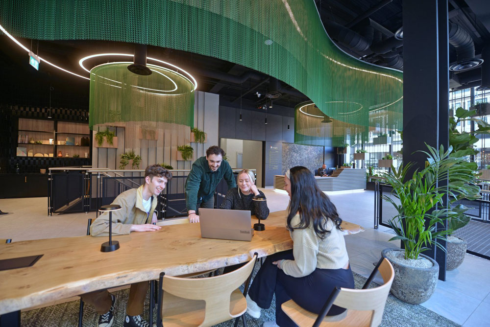 people at a long table looking at a laptop