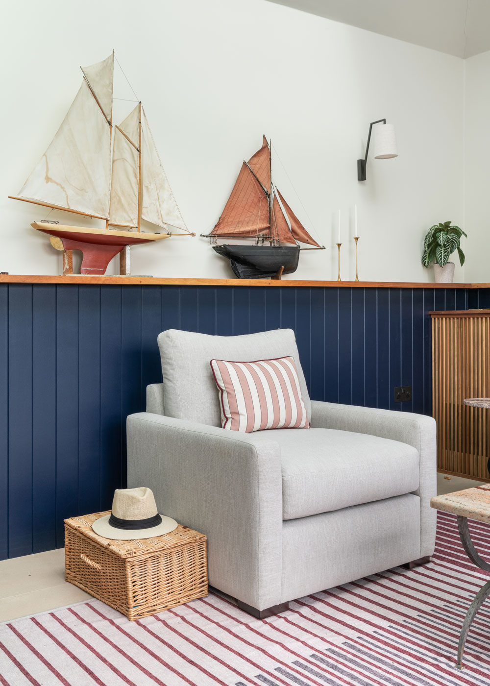 Comfy chair with striped cushion, model ships on display on the shelf behind.