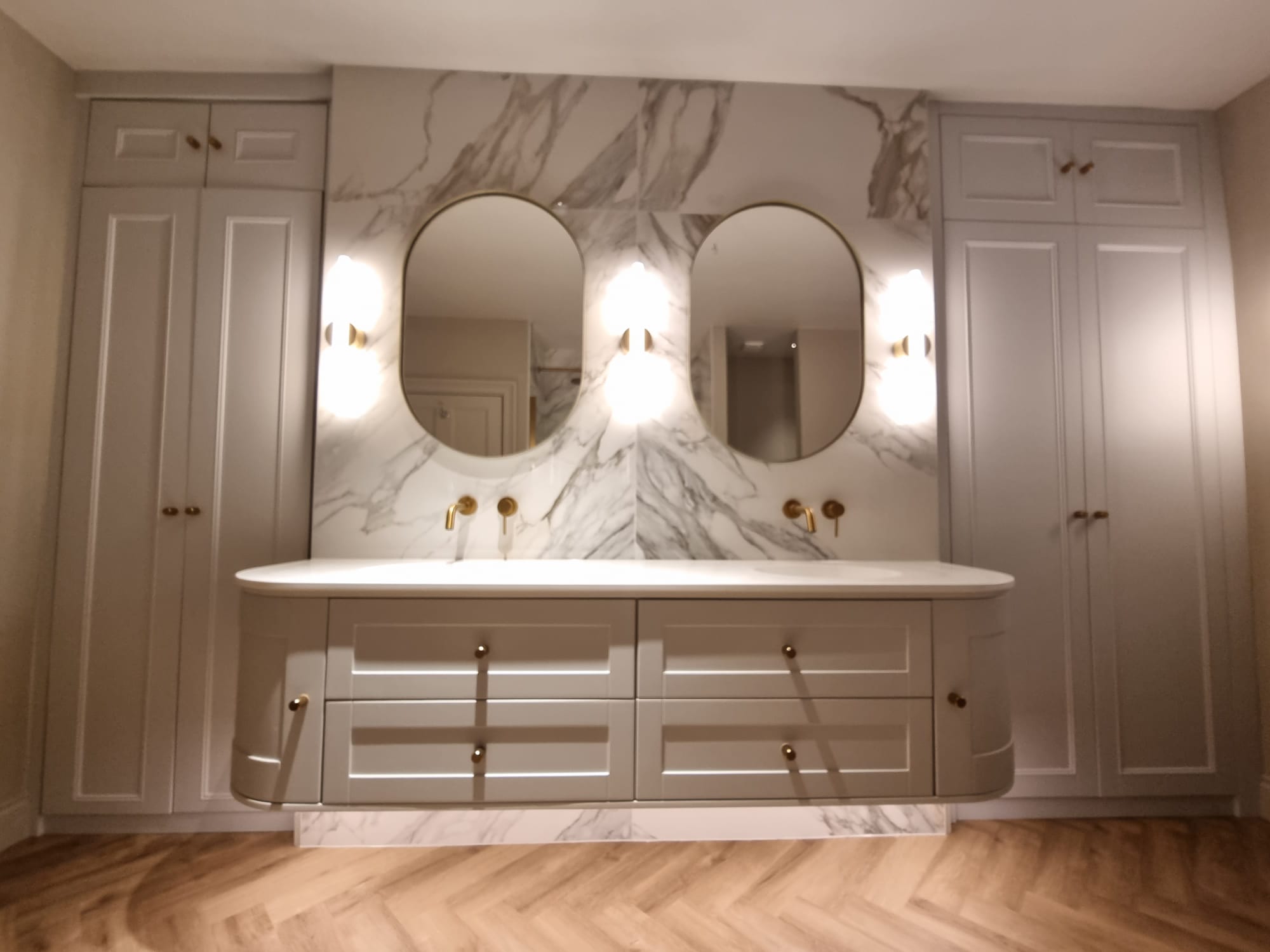 Double sinks, wall hung vanity, balanced lighting and ample storage