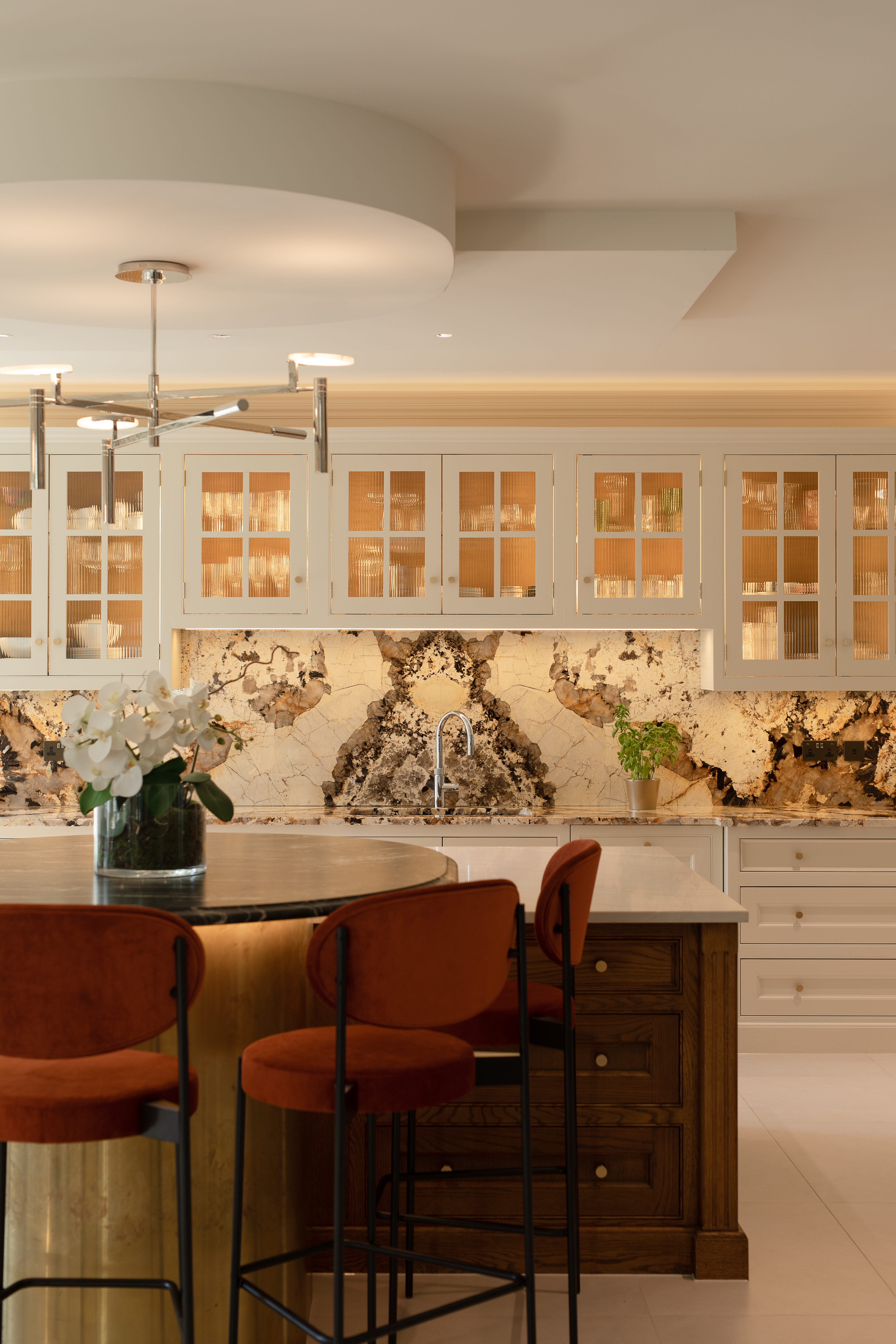 Kitchen island, stools and counter top with cabinetry and marble splashback in the background