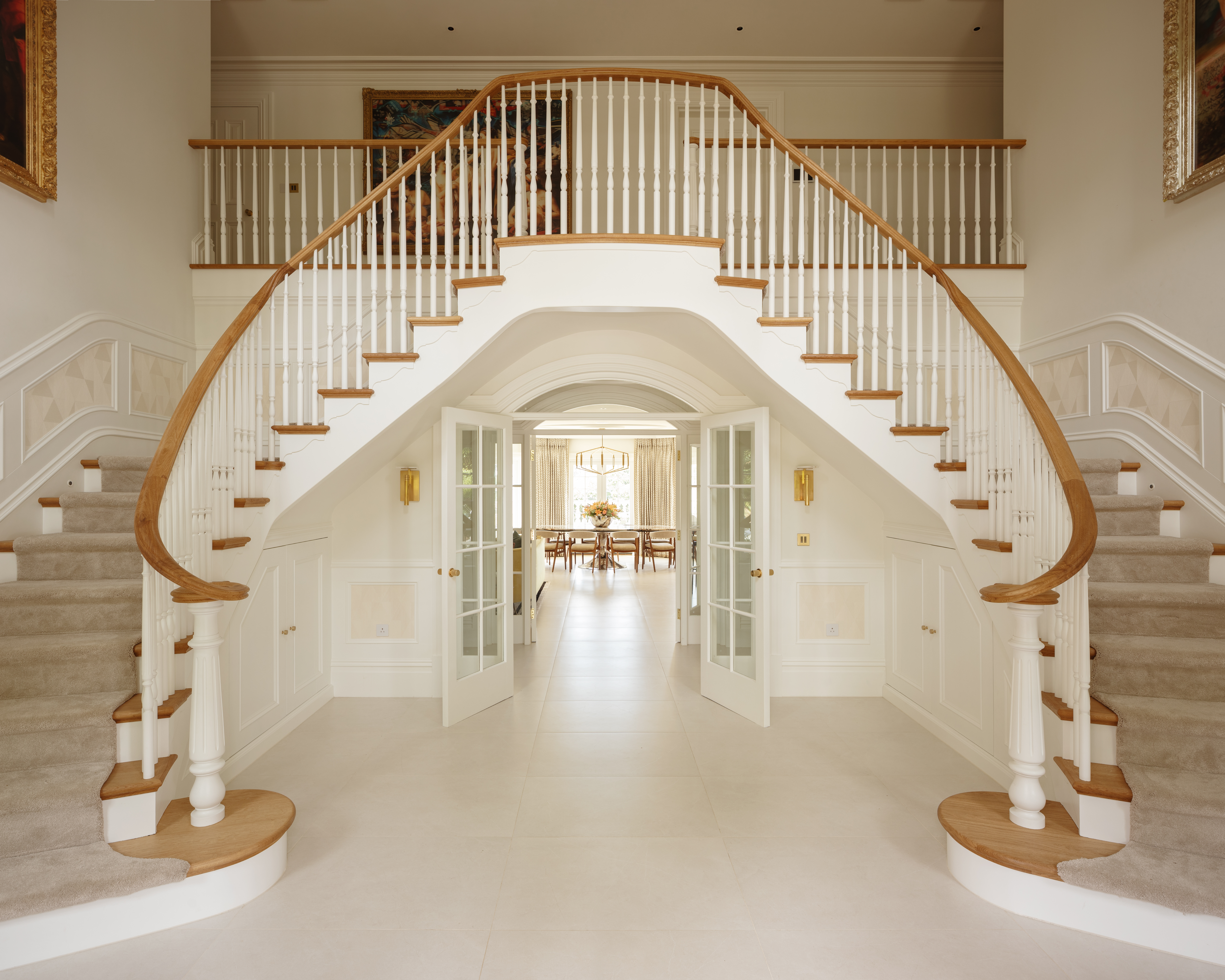 Curved double staircase in entrance hall with view through to dining room