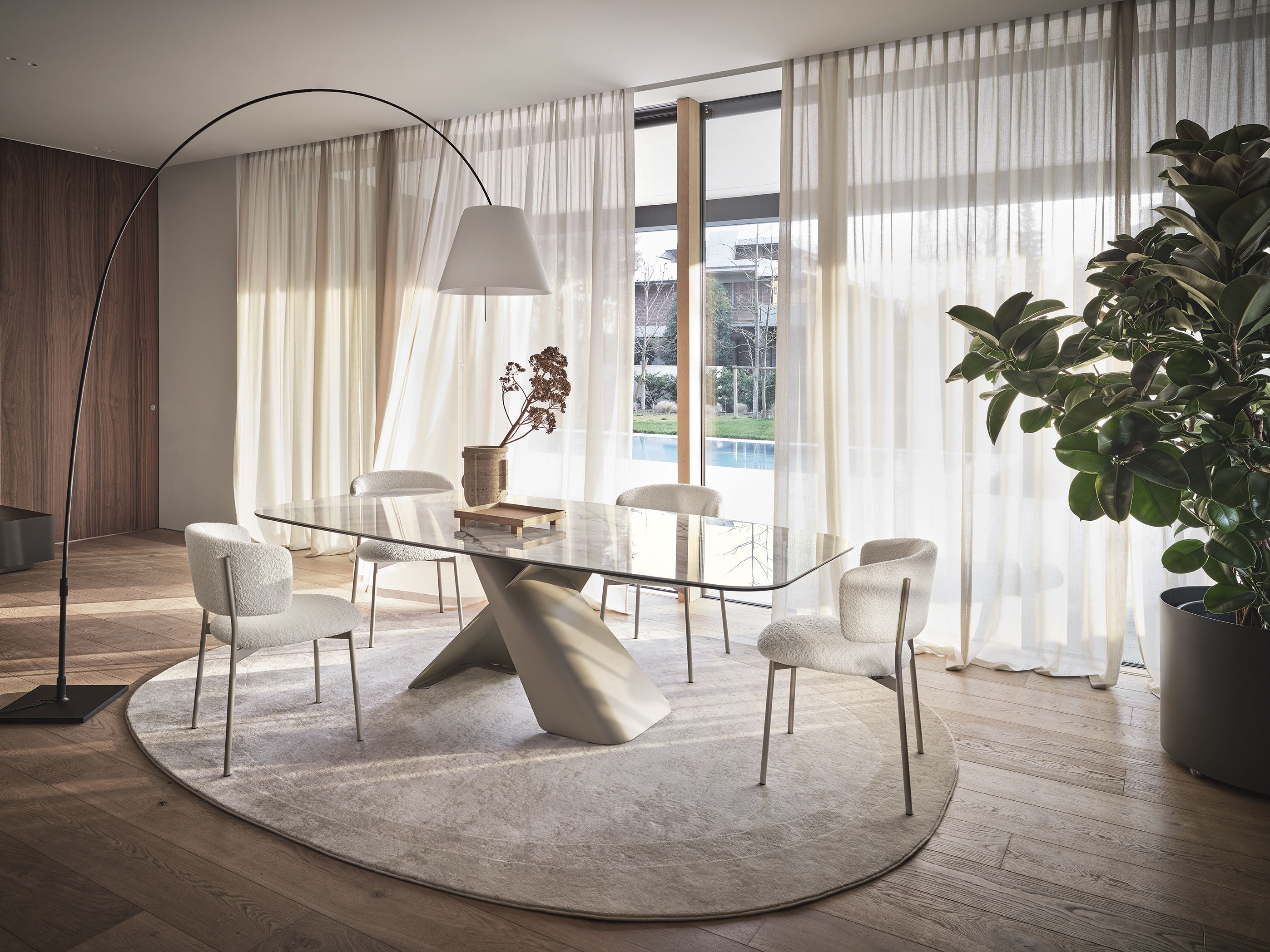 Axiom interprets the table as a fluid and contemporary gesture. The central base in curved sheet metal creates a play of visual tensions, supporting fixed or extendable tops. An iconic presence, which combines formal lightness and structural solidity.