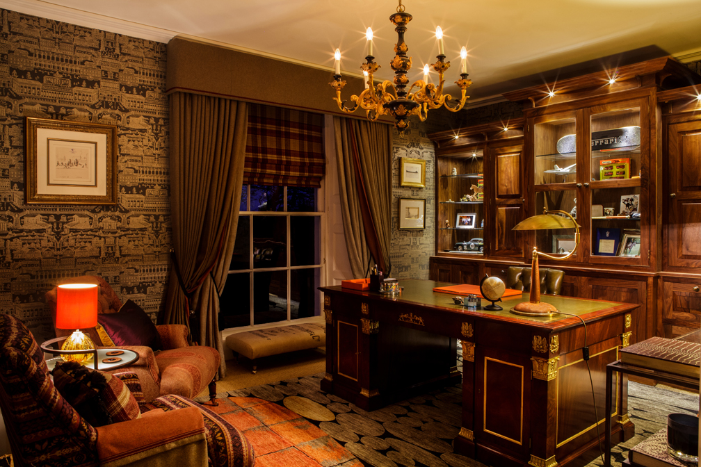 A bespoke mahogany gilded desk, leather, rich warm wools and a heavy gilt ebony chandelier offset by simple outlines of gilt, glass & steel