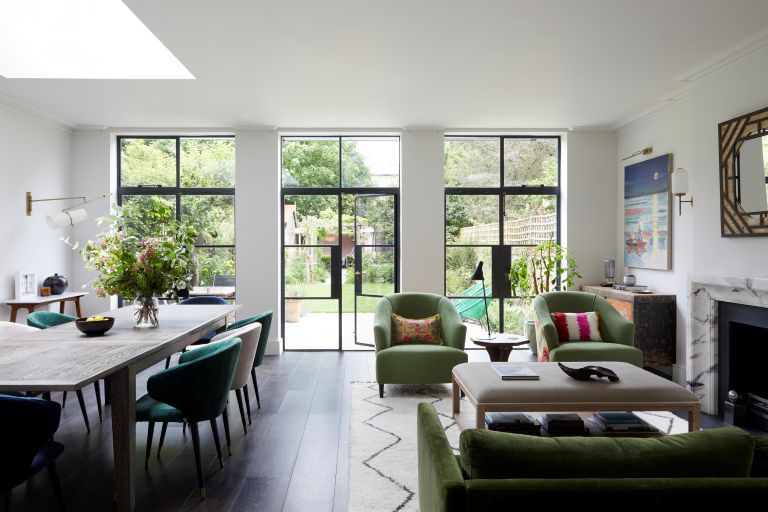 A light and airy front room, with a long table and 2 armchairs, with bright floor to ceiling doors leading to a garden