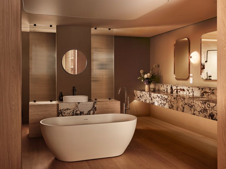 A bathroom with marble worktops and a freestanding white bath.