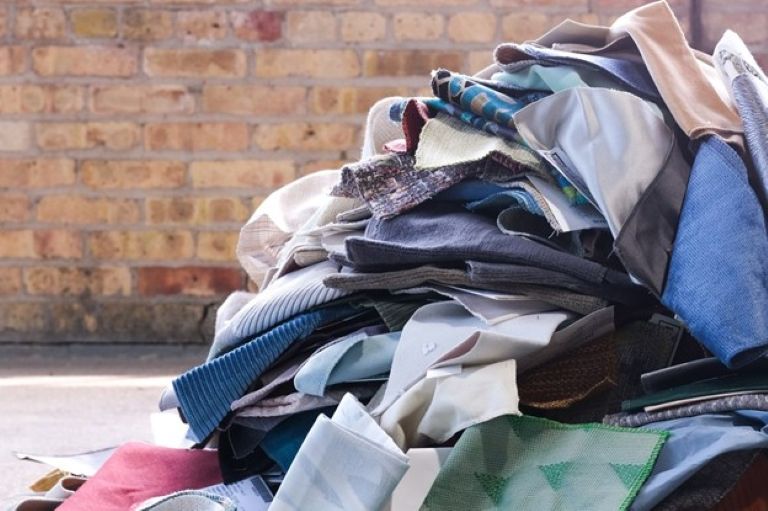 Pile of different coloured fabrics in front of a brick wall.