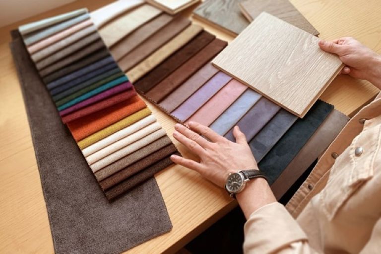 Selection of different coloured fabrics and someone touching them wearing a watch.