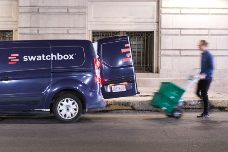 Swatchbox van with door open and a man with glasses about the load 2 green boxes into it.