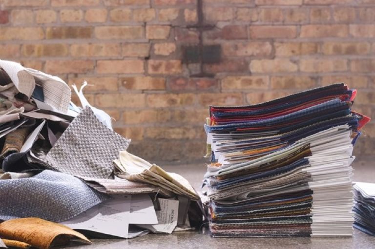 Pile of discarded fabric samples next to neat stack of labelled fabric samples.