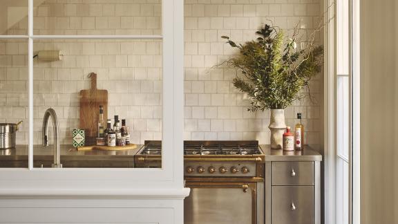 Cream kitchen with oven behind a screen with chequered flooring
